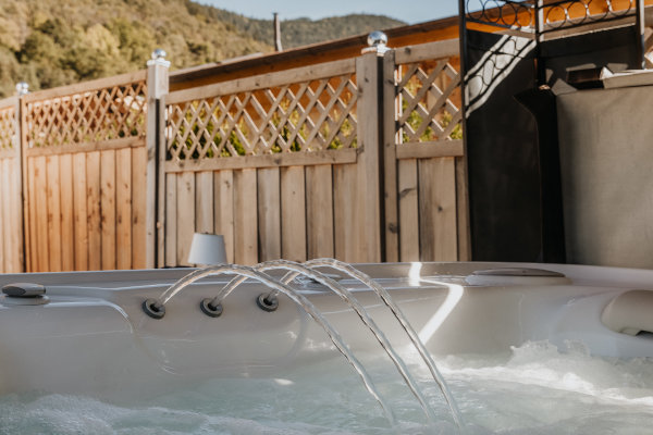 Gartendorf_Zirl_Foto_15_scaled Whirlpool im Garten. Wasser sprudelt aus den Düsen. Zaun im Hintergrund.