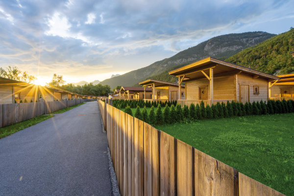 gartendorf tirol und cafe baerig-3008_Paul-Weber_scaled Ansicht der Straße, Zaun und Häuser im Hintergrund, bei Sonnenaufgang.
