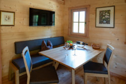 slider-14 Sitzgruppe mit Weingläsern, Brezeln und Obstkorb. Fernseher an der Wand im Hintergrund.